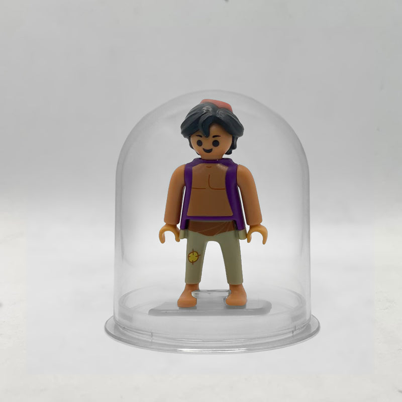 Minifigura Playmobil de Aladín con chaleco morado y fez rojo, montada sobre su peana original Playmobil dentro de la urna expositora transparente, colección Disney Kinder FCO1004