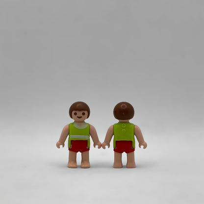Bebé moreno Playmobil FIG283 visto de frente y de espalda, con el torso verde y el pelo castaño