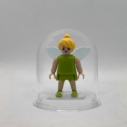 Minifigura Playmobil de Campanilla con alas transparentes, vestido verde y moño rubio, sobre su peana original Playmobil dentro de la urna expositora transparente, colección Disney Kinder FCO1005