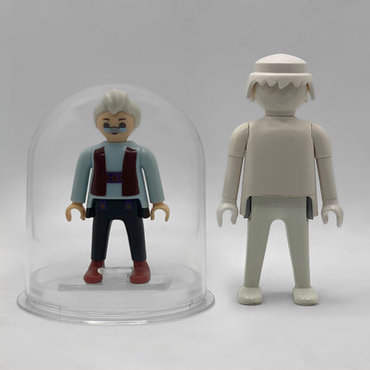 Comparativa de tamaño: Geppetto FCO1007 dentro de su urna expositora junto a una figura Playmobil estándar blanca, que no está incluida