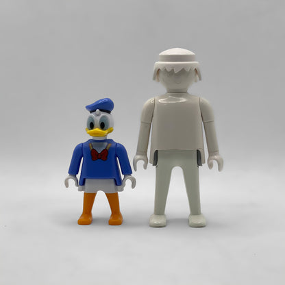 Comparativa de tamaño: minifigura Pato Donald FCO1000 junto a una figura Playmobil estándar blanca, no incluida