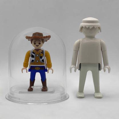 Comparativa de tamaño: Woody FCO1013 dentro de su urna expositora junto a una figura Playmobil estándar blanca, que no está incluida